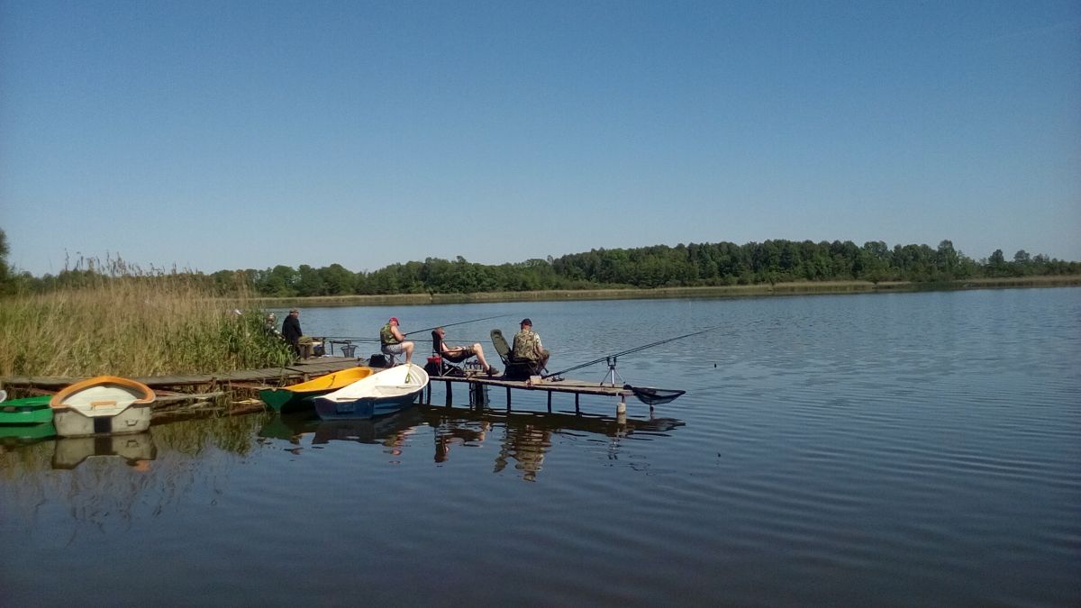 Pomost z wędkarzami i łodziami nad wodą